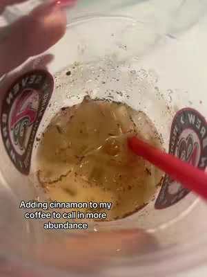 The cover image shows a close-up, overhead view of a clear plastic cup filled with a light brown liquid, ice cubes, and what appears to be cinnamon powder. A red straw is inserted into the cup. The cup is held by someone whose fingers with pink nail polish are visible.