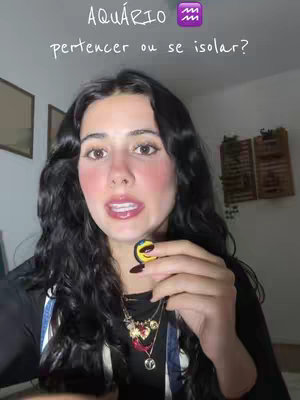 A woman with long, dark hair and fair skin is centered in the frame, looking towards the camera. She is holding a small, colorful item in her hand. The background is softly lit with some decorative items visible. Text overlays appear at the top, naming the video's subject.