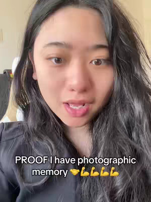 A close-up shot of a young woman with long, dark hair. The text overlay reads "PROOF I have photographic memory" with a series of hand and bicep emojis. The woman is looking at the camera and speaking.