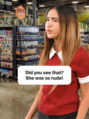 A woman in a red shirt with a white collar is in a grocery store. She is looking at the camera, and there's a text box overlay that says, 'Did you see that? She was so rude!' There are shelves of products behind her.
