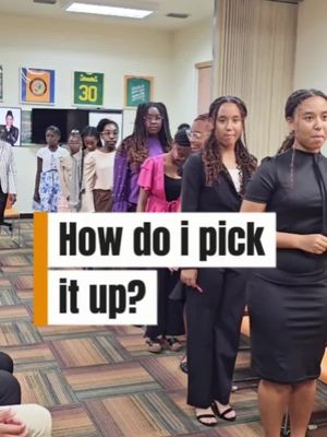 A group of young women stand in a line, facing the camera. In front of them, a text overlay reads, "How do I pick it up?" The image has a warm, indoor feel with a neutral color palette.