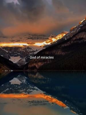 A serene landscape featuring a lake reflecting the snow-capped mountains with an orange sunset.