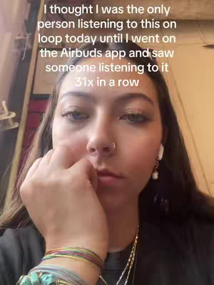A close-up selfie with a young woman looking down and to the side with a serious expression. She is wearing an earpod and has her hand up to her face, obscuring her mouth. Text overlayed reads an observation about an app.