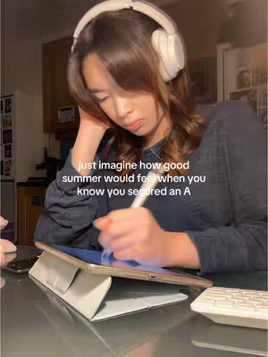 The cover image shows a young woman studying, sitting at a table with a laptop, tablet and headset. She has headphones on, is looking down attentively at the tablet and writing on it with a stylus. The background is blurred with details suggestive of a home setting. Text overlayed states, "just imagine how good summer would feel when you know you secured an A".