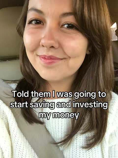 A selfie-style shot featuring a woman in a car, facing the camera with a gentle smile. She has light brown hair and is wearing a white sweater. Text overlayed at the bottom states, 'Told them I was going to start saving and investing my money'. The background suggests an interior car setting with sunlight.