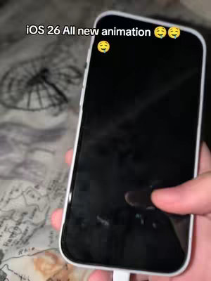 A person is holding a white iPhone, screen facing the viewer and appearing to be off. The background is a blurry out of focus texture that appear to be some type of fabric. Text overlay is at the top of the image.