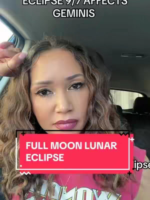 A woman with curly brown hair is in the front seat of a car while recording. The background is blurred. She's wearing a pink shirt and makeup with glitter and dark lipstick. Text overlays include "FULL MOON LUNAR ECLIPSE".