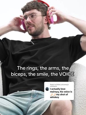 A man with a beard and glasses is shown with headphones on. Text overlayed says: The rings, the arms, the biceps, the smile, the VOICE. A comment is overlaid from the person that the video addresses.