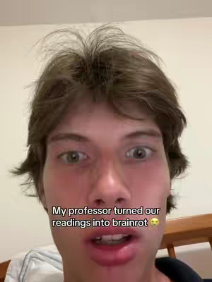 A close-up shot of a fair-skinned young man with short brown hair. His eyes are wide, and his expression suggests distress. Text is overlaid near the bottom of the frame, stating 'My professor turned our readings into brainrot' with some emoji.