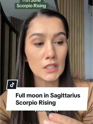 A woman with long dark hair is centered in the frame. She is speaking directly to the camera, with a serious expression. The background shows a light-colored wooden wall and a partially visible window. Overlaid text at the top reads "11th June Scorpio Rising" in a green box, and below, a white box contains the text "Full Moon in Sagittarius Scorpio Rising". A tiktok icon is present in the bottom-left.
