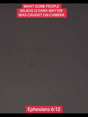 The image has a dark gray background with a red rectangular text overlay at the top. This overlay reads, 'WHAT SOME PEOPLE BELIEVE IS DARK MATTER WAS CAUGHT ON CAMERA'. Near the center of the image is a small, faint, slightly elongated dark shape. At the very bottom, within another red rectangular overlay, is the text 'Ephesians 6:12'.