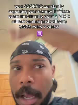 A selfie-style image featuring a Black man with a goatee and a black bandana. Text overlayed on the image reads, 'your SCORPIO constantly expecting you to know their lore when they literally share a PIECE of their vaulted past with you ONCE every 9 weeks', along with the Scorpio symbol. He looks directly at the camera with a slightly surprised expression.