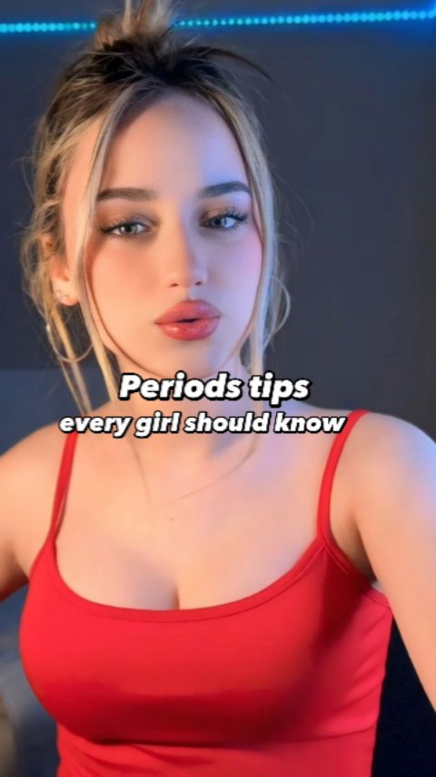 A well-lit selfie-style shot of a woman with blonde hair and wearing a red tank top. The background is dark, and the text overlay reads 'Periods tips every girl should know'. The woman is looking at the camera with a neutral expression. There is a soft, blue lighting effect on the top.