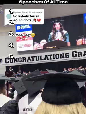 The image shows a scene from a graduation ceremony. In the foreground, there are multiple graduation caps. In the background, a person is speaking at a podium, with a large screen behind them showing text. The overall composition suggests a moment of a graduation speech. On upper left side of the screen several texts with numbers as label are added. The images seems to be taken from a mobile phone.
