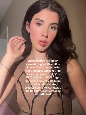 A young woman with dark hair and a natural complexion is shown from the chest up. She is wearing a top that has a textured nude fabric in the middle with a geometric pattern, and black straps. The background is a soft, warm tone, with minimal details. She is looking slightly toward the left of the frame, and speaking. Text is overlaid on the image in white.