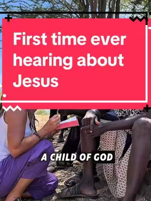 The image shows a scene of cultural exchange, with a vibrant red rectangular overlay at the top containing white text that reads," First time ever hearing about Jesus". Below, two individuals are seated and appear to be engaged in a conversation. One person, with fair skin and light-colored hair, is dressed in a casual white top and purple pants, and is holding a book. Beside them is a person with dark skin seated, and who has a printed patterned cloth. The bottom of the frame contains the text "A CHILD OF GOD". The background is a natural setting under a bright sky.