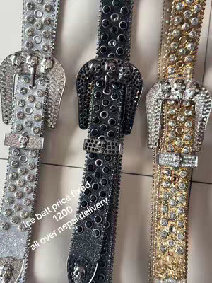 The image shows three belts with buckles in silver, black, and gold. The belts are arranged vertically and have the buckles at the top. The belts feature studs, and the buckle shape includes a skull.