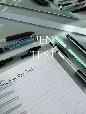 A close-up shot of various pens and writing instruments arranged on a white surface. A sheet of lined paper with handwritten text is in the foreground. The words 'PEN TEST' are overlaid on the image. The arrangement and lighting suggest an ASMR or study-related theme.