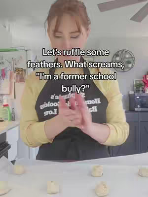 A woman in a yellow shirt and black apron rolls dough on a counter with text overlayed reading 'Let's ruffle some feathers. What screams, "I'm a former school bully?"' in a kitchen setting.