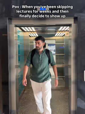 A man in a green shirt and white pants walks towards the camera out of an elevator. The background is the interior of the elevator, with reflective metal walls and a light fixture. Text overlays the top, reading 'Pov: When you've been skipping lectures for weeks and then finally decide to show up'.