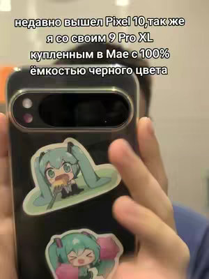 A person holding a black smartphone with a sticker of a green-haired anime character. The phone's camera lens is visible. Text is overlaid on the top of the image.