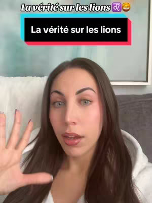 A woman with long, dark brown hair and light skin is centered in the frame, looking directly at the camera. She has expressive blue eyes, and her lips shine with gloss. Behind her is a soft background, including a pillow and part of a framed piece of art. The overlay displays text.