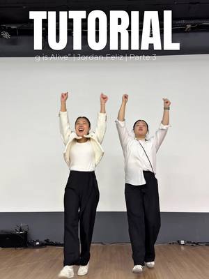 Two young women are shown in a dance studio, enthusiastically raising their arms in a gesture of excitement or celebration. They are both dressed in black trousers and white tops, with one wearing a jacket. Above them, the word 'TUTORIAL' is displayed prominently.