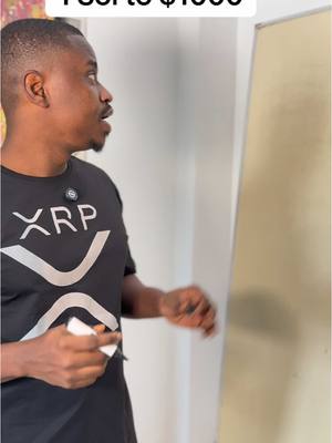 A man in a black XRP t-shirt is gesturing towards a whiteboard with text overlayed at the top.
