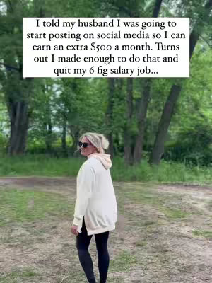 A woman is seen from the side, walking outdoors. She wears a white oversized hoodie, black leggings, and sunglasses. A text overlay towards the top of the image provides context, while the setting appears to be a wooded area.