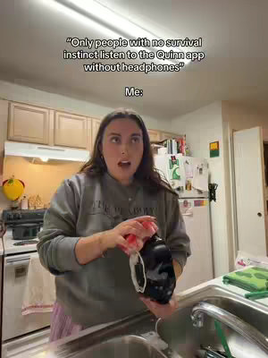 A woman with long dark hair stands in a kitchen looking surprised with her mouth open. She is holding a black object with white detailing and a red sponge in her hands. The background shows a kitchen. Above her head is text in white font.