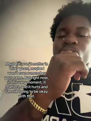 A close-up shot shows a Black man with dark hair, a nose ring, and a gold chain bracelet holding his hand up to his face, partially obscuring it from view. Text overlays the image, conveying a reflective message.