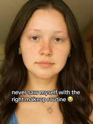A selfie-style shot shows a young woman with medium-length dark hair against a neutral background. She has light skin, wears small silver hoop earrings, and a delicate heart-shaped necklace. The text overlayed is in a bold, white font.