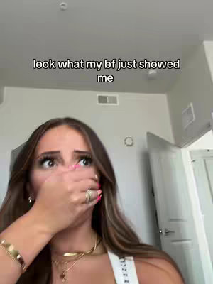 A woman is shown close up, covering her mouth with her hand as she looks towards the camera, eyes wide, conveying shock. The hook text is superimposed over her shot and the background is a simple interior.