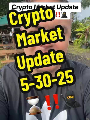 A selfie-style video cover image featuring a man centered in the frame. The background appears to be an outdoor setting with greenery. The man is wearing a black t-shirt and the video's title is overlaid on the image with a yellow font and black outlines. Elements include the text “Crypto Market Update”, the date “5-30-25”, along with several exclamation points and emojis (an hourglass and a ninja). The composition is a medium shot with the focus on the upper body and face of the content creator. The overall tone is informative.