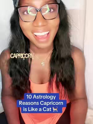The cover image is a selfie-style shot of a woman with dark hair and glasses, smiling and looking upwards. She has a makeup, and a 'Capricorn' text overlay framed in gold. A lower blue rectangle contains the text '10 Astrology Reasons Capricorn is Like a Cat' with a small cat icon.