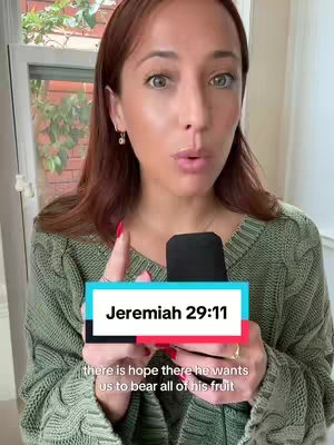 A woman with red hair, wearing a green sweater, holds a black microphone. A text overlay reads "Jeremiah 29:11" with a supporting quote below. The background includes a window.