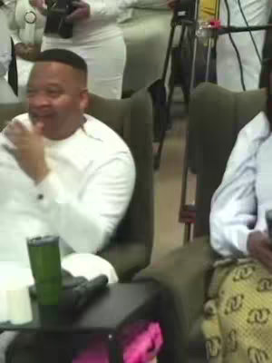 The cover image shows a man of African descent sitting in a chair and smiling. He is wearing a white shirt. The background is blurred, but other people and a camera are visible.