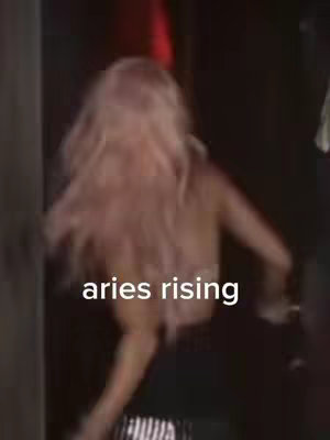 The cover image shows a person from behind, walking into a dark space. The person has long, light pink hair and is wearing a black outfit. Text is overlaid on the image that says "aries rising".