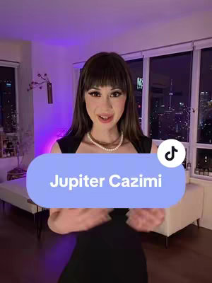 A woman in a black top and pearl necklace stands in front of a window. There's text in a light blue box that says 'Jupiter Cazimi', overlaying the image.