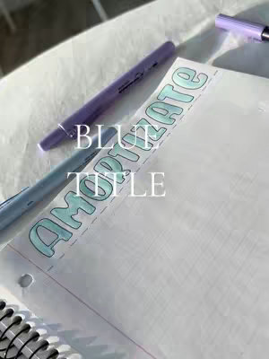 The image is a close-up shot of a notebook page with some words and two pens. The notebook page is white with blue lines, and the words 'BLUE' and 'TITLE' are written in white, with a light-blue outline and are above the words 'AMORTITATE'. The top of the paper is decorated with a pastel blue handwritten word, and two pens, one light and one dark purple, are placed diagonally across the top of the image. The background is blurred, with a soft, off-white color, and the lighting is natural, creating soft shadows.