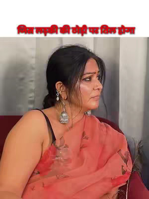 A woman in a red printed saree is seated in a chair. The background appears to be an interior with curtains or drapes. The hook text is written in a red banner.