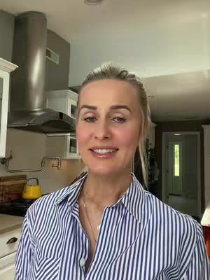 A woman with blonde hair smiling in a kitchen, with a striped shirt.