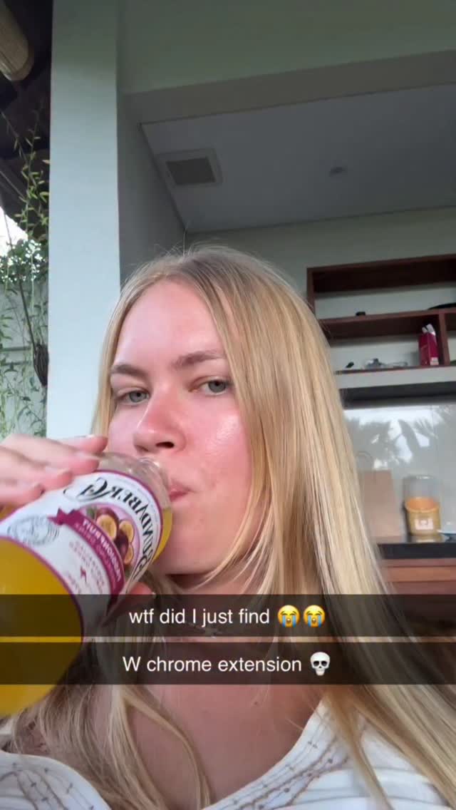 The cover image is a selfie-style shot featuring a woman drinking from a yellow-colored juice bottle. The woman is facing towards the camera, with her blonde hair flowing down, and she appears to be outdoors. Text overlaid on the image reads "wtf did I just find" followed by two crying face emojis, and "W chrome extension" with a skull emoji. The background is slightly out of focus but suggests a lush outdoor setting with potential greenery and architectural elements.
