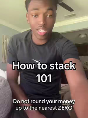 A young Black man is centered in the frame, looking towards the viewer and talking. Overlay text reads "How to stack 101" and "Do not round your money up to the nearest ZERO". The background includes a ceiling fan.