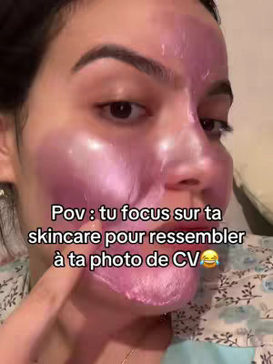 A close-up selfie of a person’s face covered in a pink skincare mask. Text overlayed on the screen describes the scene.