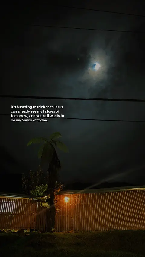 A night scene featuring a dark sky with clouds and a moon partially visible. A palm tree and a wooden fence are in the foreground, illuminated by an orange light source. Text in the upper left corner provides a religious quote.