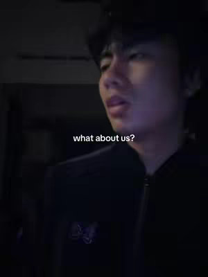 A young man looks slightly off-camera, with soft lighting illuminating his face. Text overlayed in white reads "what about us?"