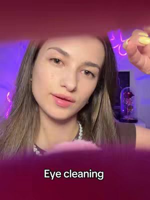 A woman with long highlighted hair and light makeup is looking towards the camera. The background has a purple glow, and a text overlay at the bottom says 'Eye cleaning'.