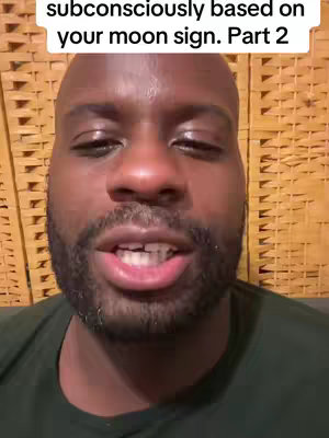 A close-up video shot of a Black man with a bald head and well-groomed beard, speaking directly into the camera. The background is a woven, light-brown surface. Text overlay on the top left corner reads, 'subconsciously based on your moon sign. Part 2'