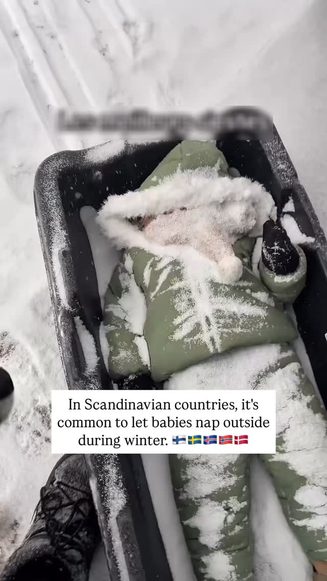 A top-down shot shows a baby bundled in a green snowsuit lying in a black sled, covered partially in snow. The background is white with tracks visible, suggesting a snowy outdoor setting. Text is overlaid, discussing the practice of letting babies nap outside in cold Scandinavian countries. The overall composition is simple, highlighting the baby amidst the snowy backdrop.